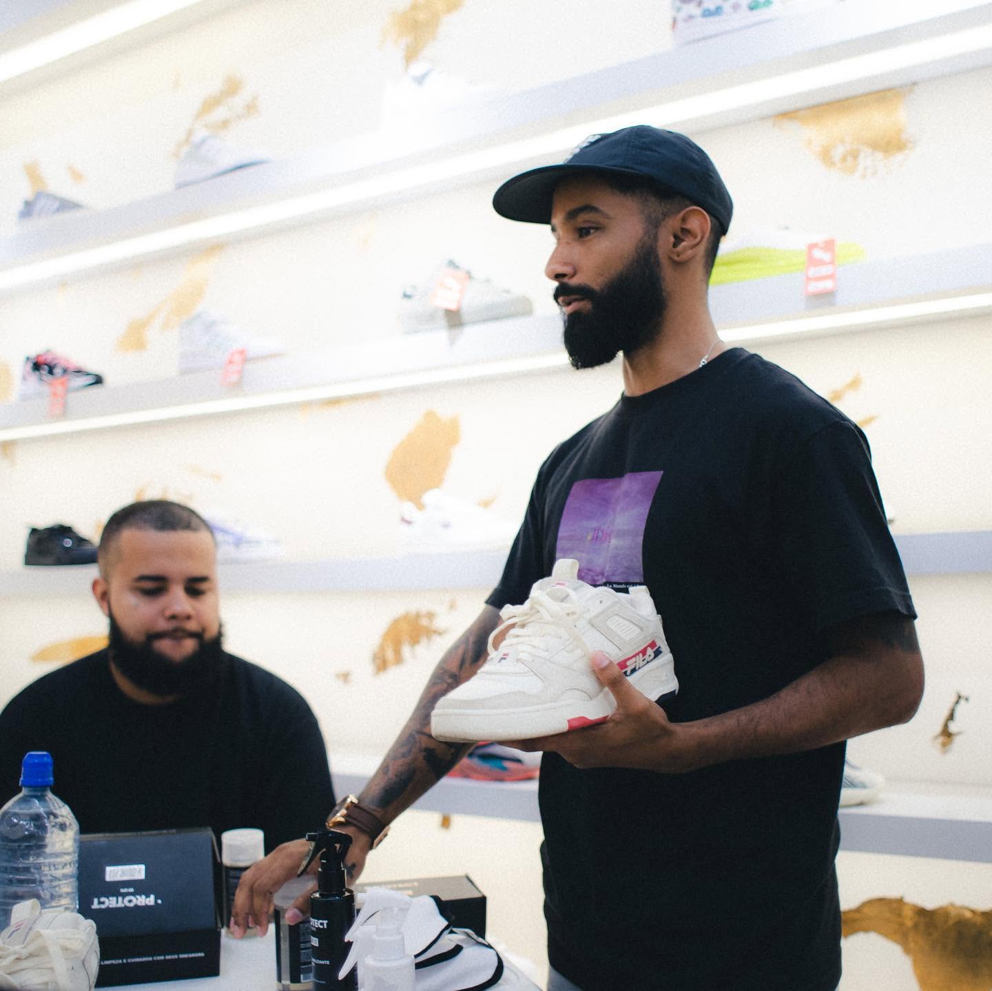 Tiago Oliveira em loja de sneakers segurando um tênis branco